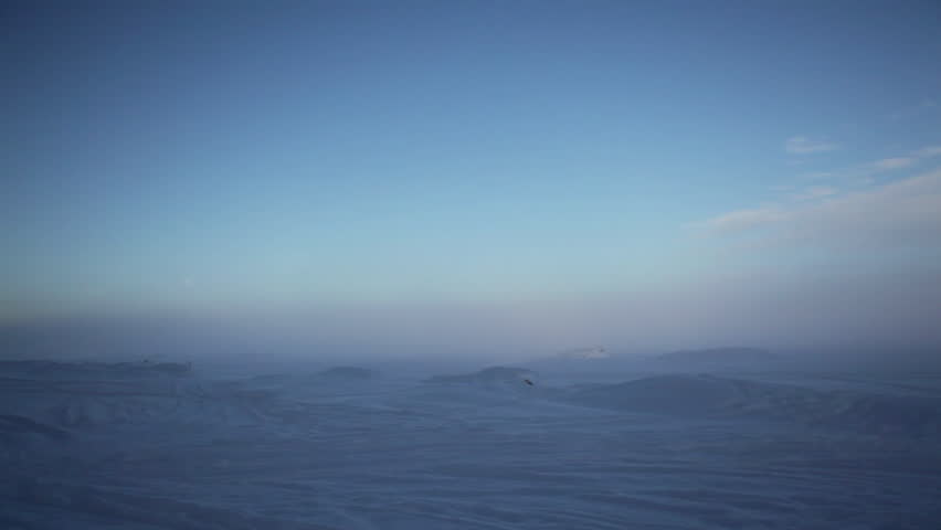 The Apostle Island National Lakeshore on frozen, snow-covered Lake Superior. Ice hummocks and moon visible in pastel blue and pink light of misty dawn. Static shot, with slow pan in both directions.
