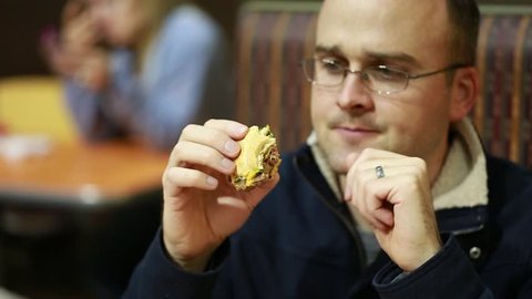 A man eating a cheeseburger at a fast food restaurant