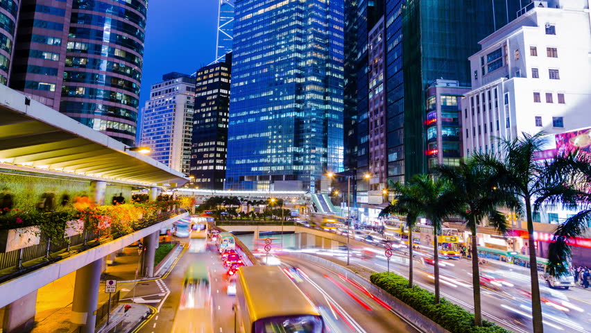 Busy City Night Timelapse. Central. Hong Kong. 4K Tight Shot. Office buildings with busy traffic across the highways at rush hour.People on sidewalk and footbridge. People line up for public cars. 
