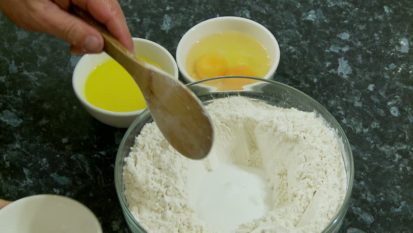 Adding melted butter and eggs to a mixture of flour and sugar to make dough