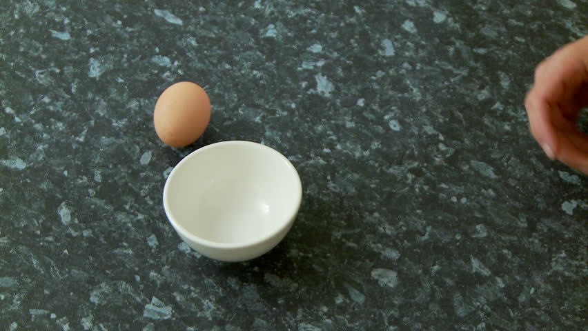 Cracking an egg into a small bowl