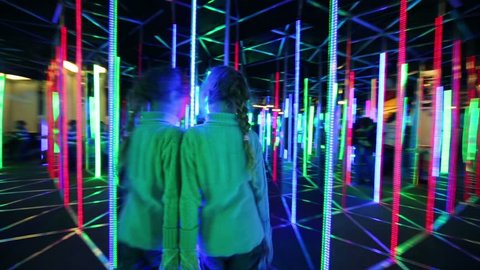 Little girl walks through labyrinth illuminated with colour lights