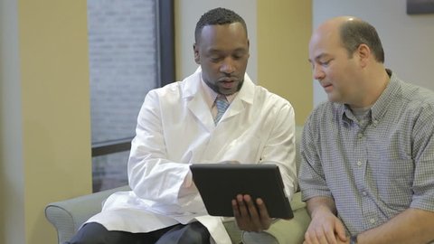 African American doctor talking with patient in hospital. Professional African medical physician going over medical information in medical center.
