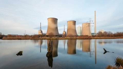 A coal-fired power station in river landscape with dead trees