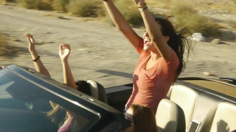 Girls Enjoy A Ride In A Convertible With Their Arms Raised