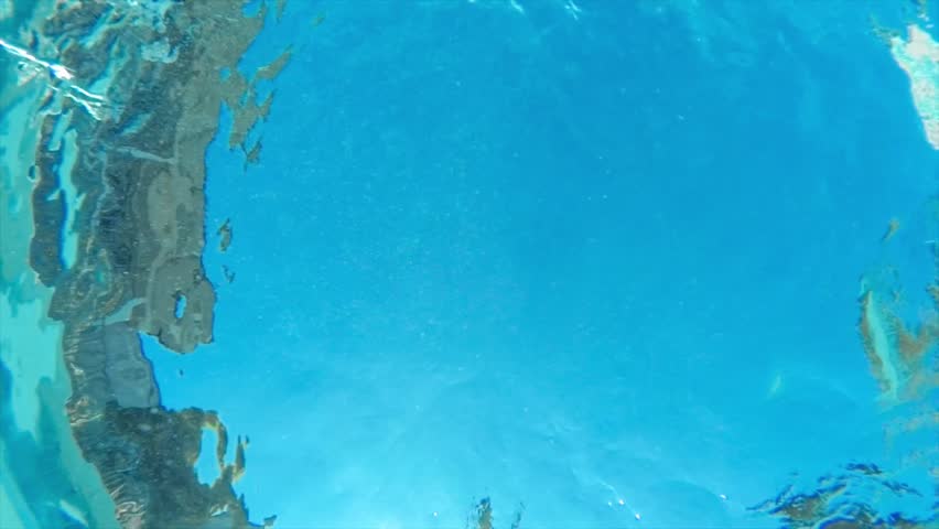 Slow motion low angle underwater shot of man doing canon ball jump in swimming pool