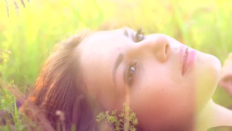 Beautiful Girl Lying on the Meadow and Dreaming. Enjoy Nature. Beauty Woman outdoors. Spring Field. Close up Slow Motion Footage 1920x1080p. Slowmo. High Speed camera shot