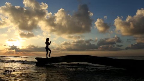 Young woman practicing yoga on the beach at sunrise in the caribbean