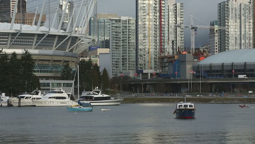 Looking across False Creek at Yaletown condominiums from the south shore. Paddlers practice in dragon boats as a running race takes place in the background. Vancouver, British Columbia, Canada.
