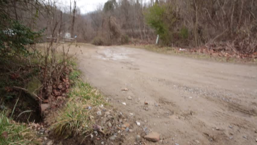 West Virginia State Patrol Cruiser Passes Left to Right on Dirt Road