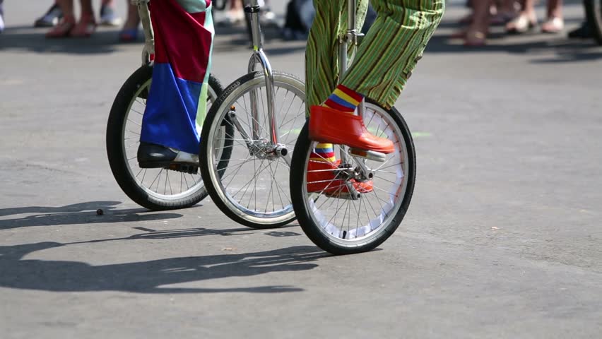 Feet of two clowns in colored clothes riding on unicycles outdoor Royalty-Free Stock Footage #5730062