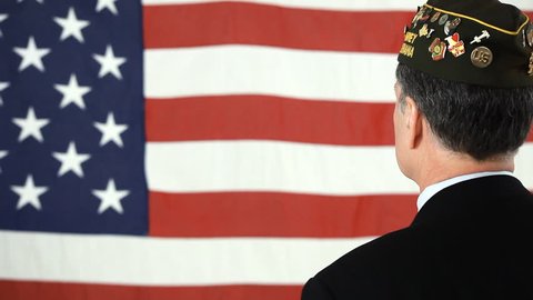 A man in a VFW cap facing an American flag and saluting. Dolly Shot