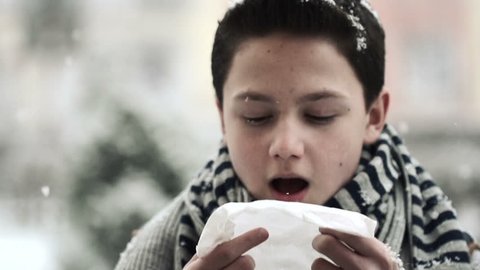 Sick teenage boy sneezing in snowy weather
