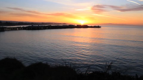 A beautiful sunrise comes up over the bay and wharf in Santa Cruz, California.
