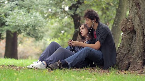 Music on picnic. Young loving couple listening to the music on picnic together
