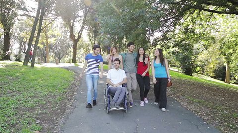 Handicapped young man in park with his friends