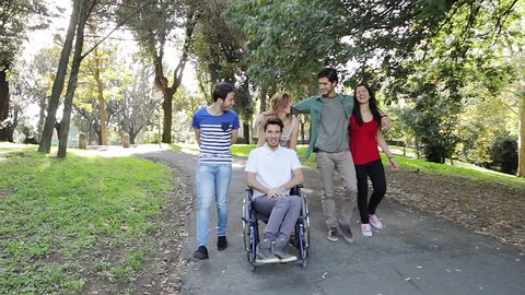 Disabled young man with a group of friends sit in park