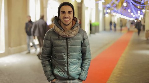 Man walking outdoors at night and smiles on the camera