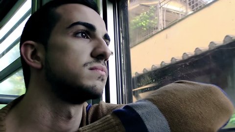Young man in a car of a train and looks out of the window