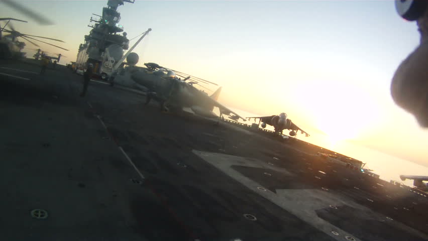 Morning sun off of battle ship. Silhouette of military aircraft on Navy aircraft carrier perorating for combat. 