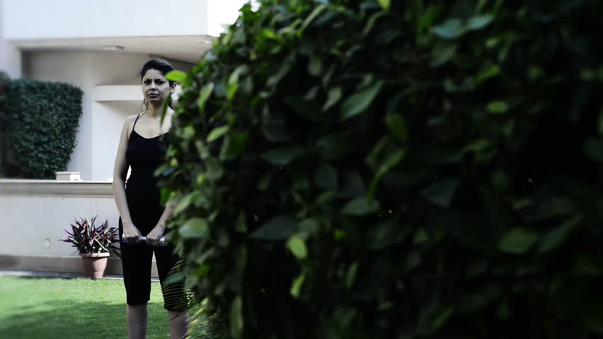 Shot of a woman exercising with dumbbell in lawn