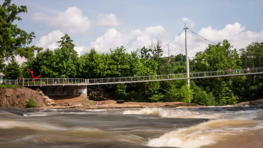 Time lapse shows fast moving people walking across The Liberty Bridge over Falls Park on The Reedy River in Greenville, South Carolina

