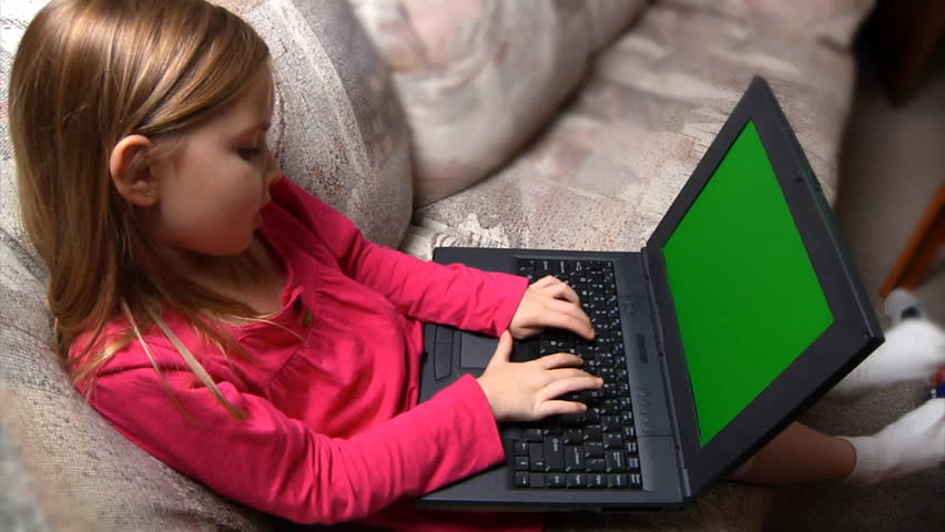 A little girl uses a laptop.