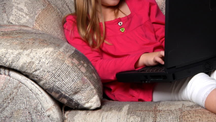 A little girl uses a laptop.