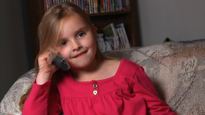 A little girl talks on a cordless phone.