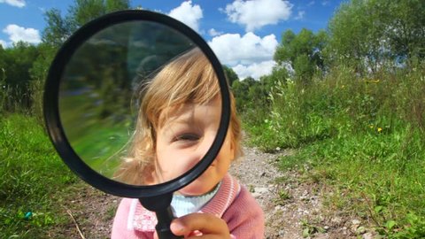 little girl looks in camera through a magnifier 
