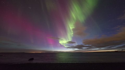 Colorful aurora (northern lights) display over the ocean at sunset. Reykjavik, Iceland