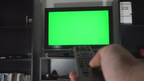 Male Hand With TV Remote Switching Channels On A Green Screen TV Point Of View