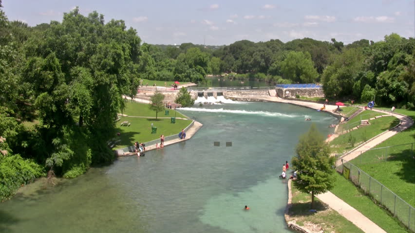 Video of people toobing or tubingand swimming in the flow of the Guadalupe River in New Braunfels Texas. Waterfall and calm water. Summer fun and excitement. Tube and raft trips.