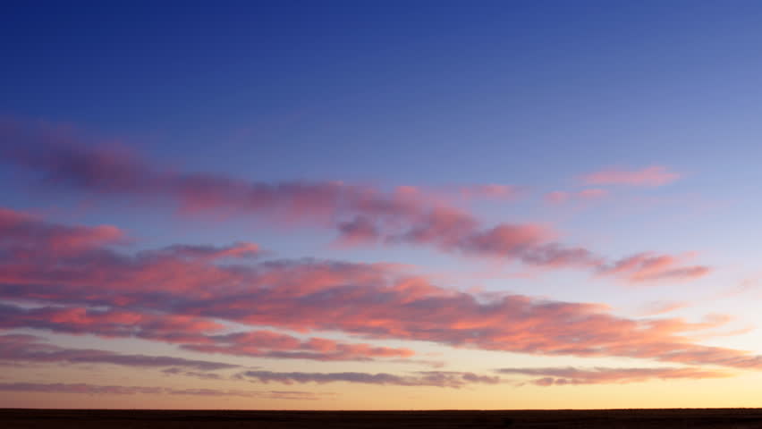 Clouds turns to vibrant pink at sunrise in farmland in eastern Colorado.