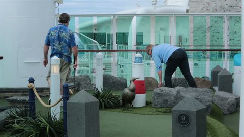CARIBBEAN OCEAN - JAN 2014: Couple play Miniature golf cruise ship Caribbean vacation. Golf fun, sport and recreation. Husband and wife warm adventure growing in love and friendship.