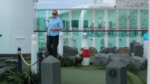 CARIBBEAN OCEAN - JAN 2014: Couple play miniature golf cruise ship vacation. Golf fun, sport and recreation. Husband and wife building love and friendship. Summer escape and vacation. Warm adventure.