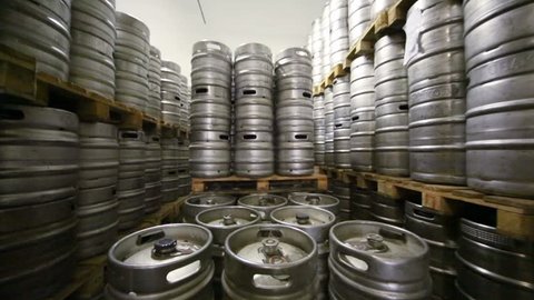 Movement along high rows of metal beer kegs in warehouse