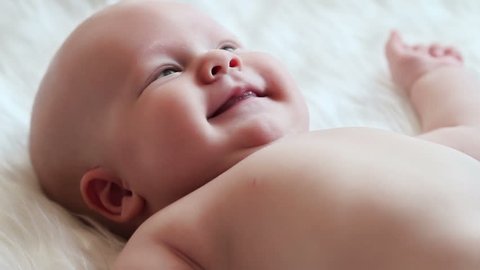 Happy newborn baby smiling close-up in white bed