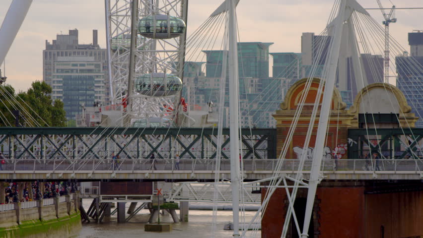 close-up of pedestrians and train on Hungerford Bridge in London