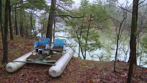 CIRCA MARCH 2013: Neglected paddle boat sits aside a river bank in the woods on a cloudy day.