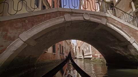 View from a gondola as it glides under a bridge in canal
