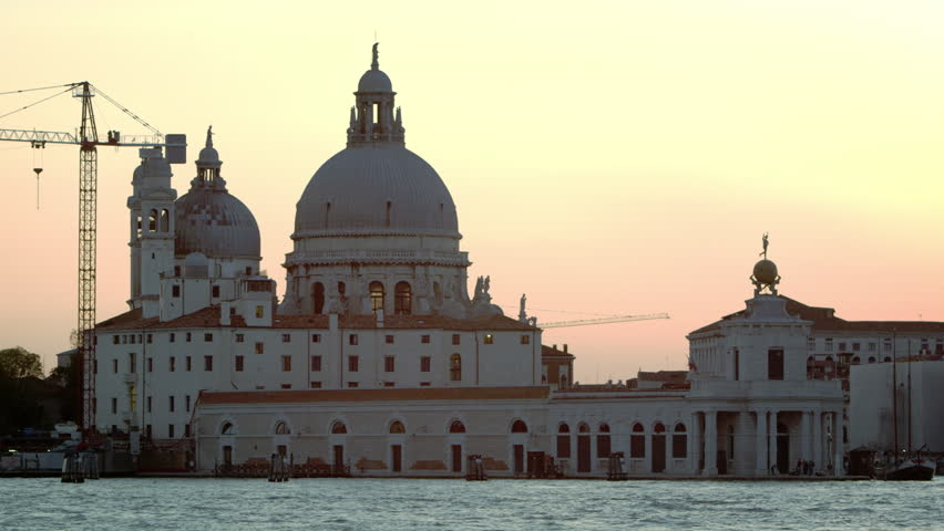 Static shot of Santa Maria della Salute and boats in the canal at sunset