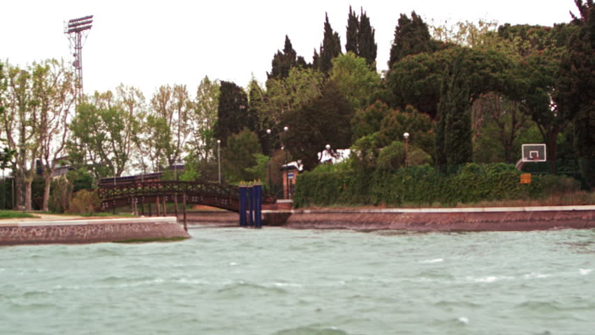 Tracking shot of a wooded park in Venice, from a water taxi
