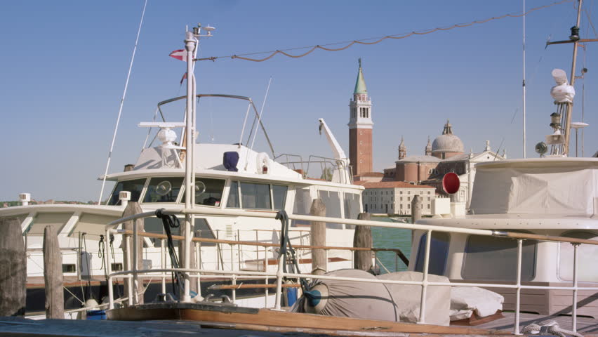 Static shot of a boat docked at a marina with the Island of San Giorgio in the