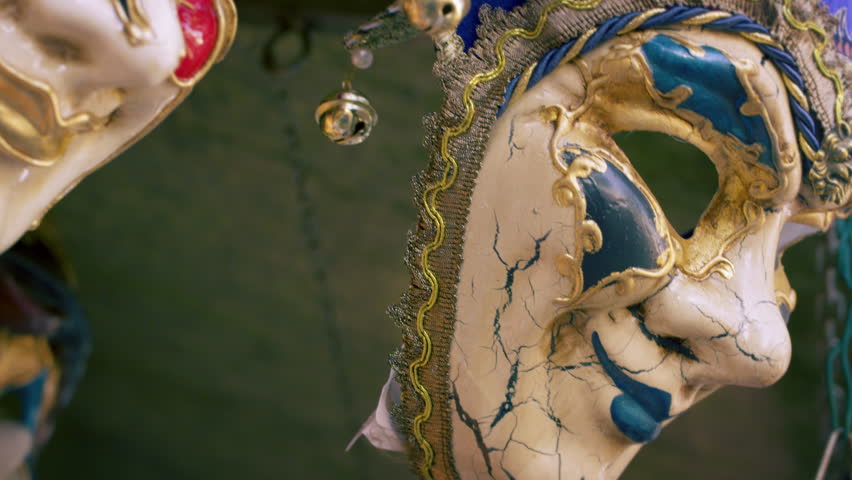 Close up tilting down shot of several elegant carnival masks blowing in the