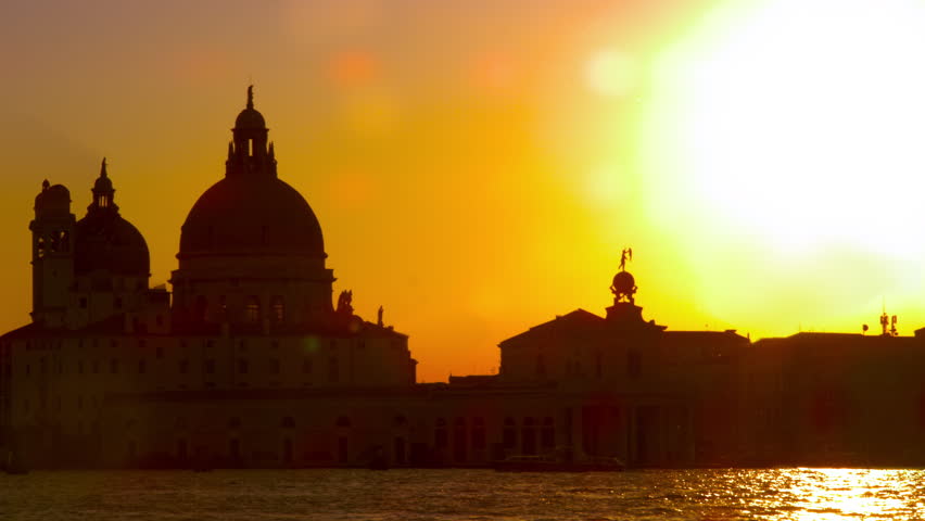 Slow motion, sun lens flare with Santa Maria della Salute in the setting sun