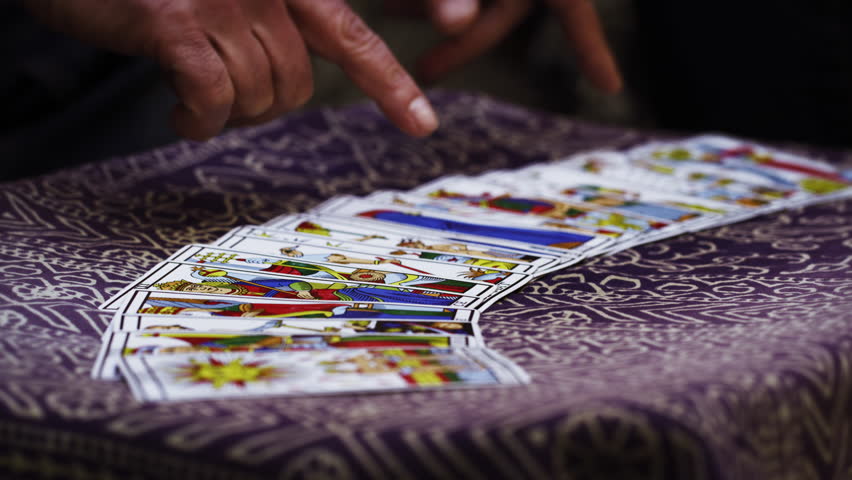 Close-up footage of two pairs of hands shuffling and adjusting tarot cards