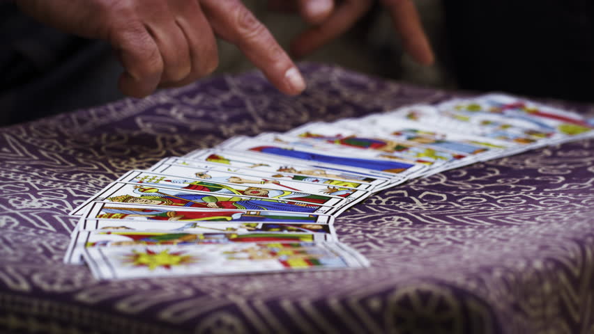 Close-up slow motion footage of hands shuffling tarot cards