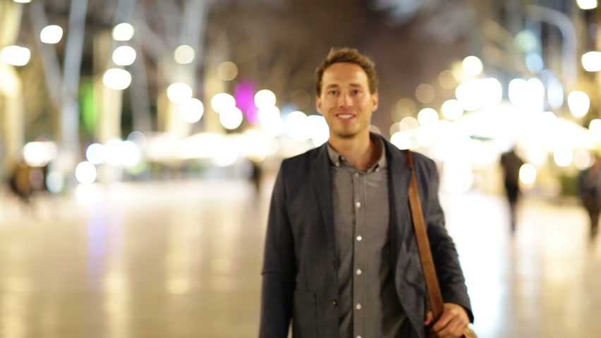 Business man giving thumbs up success hand sign. Happy smiling casual businessman walking into focus smiling happy and successful at night on La Rambla, Barcelona, Spain. Young casual professional man