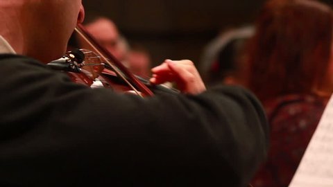 Male performs lead violin sole part playing at classical concert. Professional symphonic orchestra musicians at rehearsal, accompanying opera singer at theatre. Audience enjoying music, inner harmony
